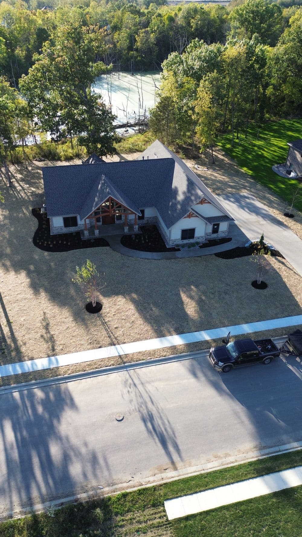 Aerial view of a modern home with landscaped yard and nearby natural scenery.